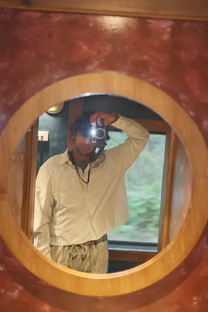 Me taking a photo of myself in a round mirror on a train, the camera held up to my eye.