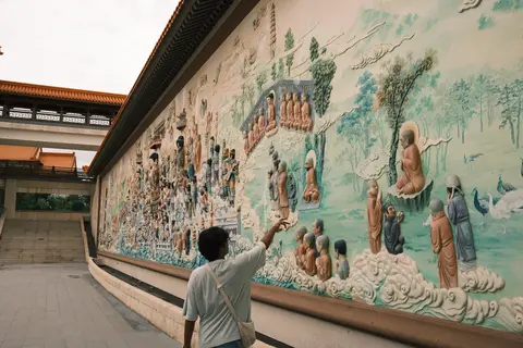 Me pointing at a long painted mural on a temple wall.