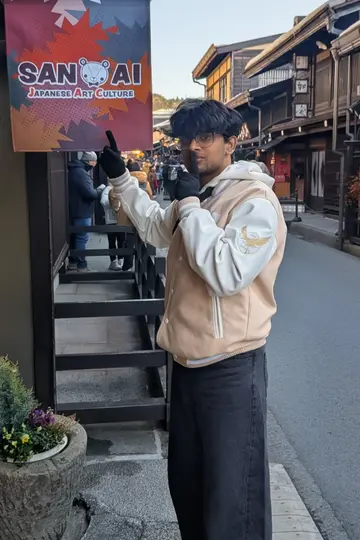Me pointing up at a shop sign on an old wooden street in Japan.