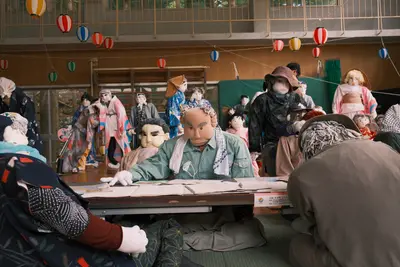 A room full of life-size handmade dolls seated at desks under strings of paper lanterns.