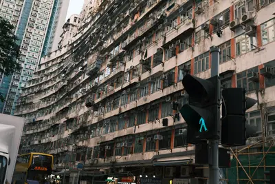 A curved wall of old apartment blocks seen from the street, a green pedestrian light in front.
